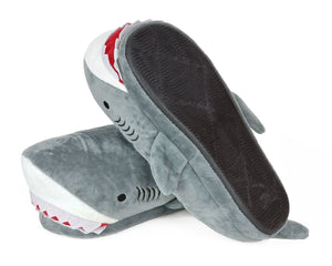 Pair of plush shark slippers, one slipper is turned upside down to show a black molded sole with non-slip tread